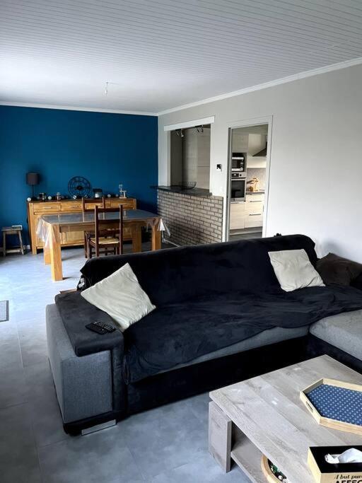 uma sala de estar com um sofá preto e uma mesa em Maison avec jardin 