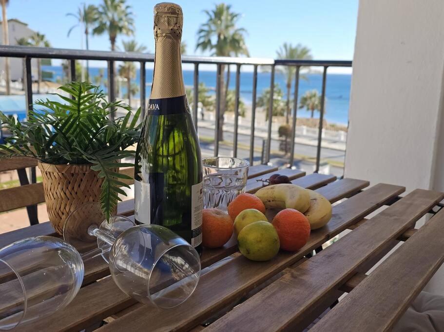 una botella de vino en una mesa de madera con fruta en Spacious Front Line Beach 3 Bedroom apartment with amazing sea views a few steps from the beach en Benalmádena