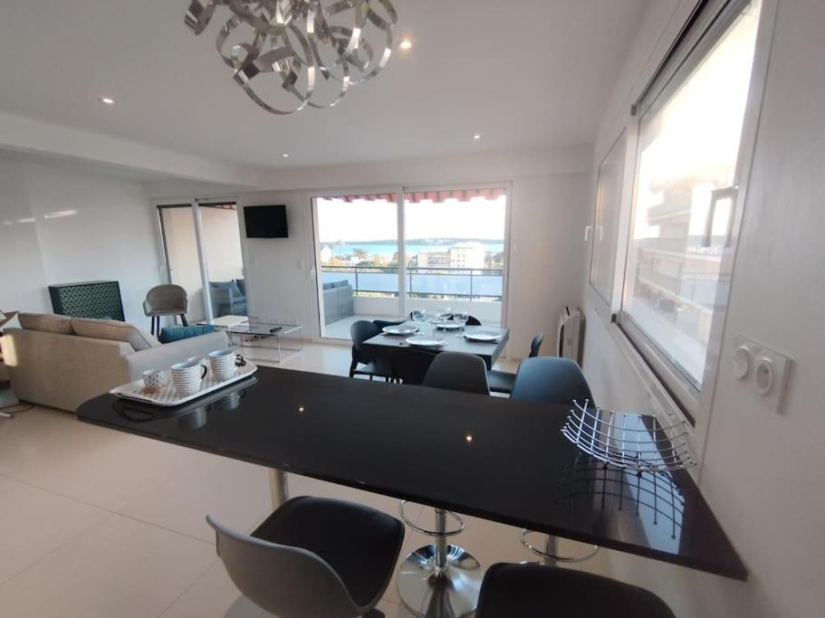 - un salon avec une grande table et des chaises noires dans l'établissement Cannes Vue mer T2 61m²+ parking, à Cannes