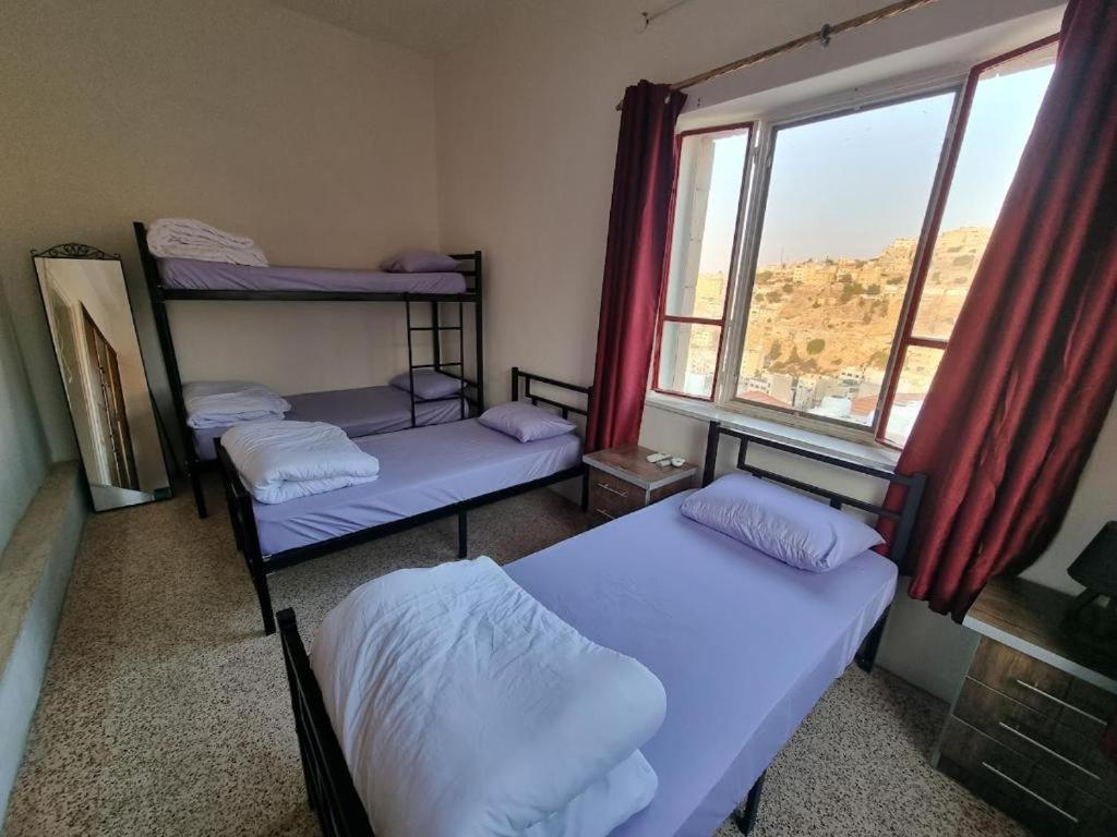 a room with three bunk beds and a window at Rainbow House in Amman