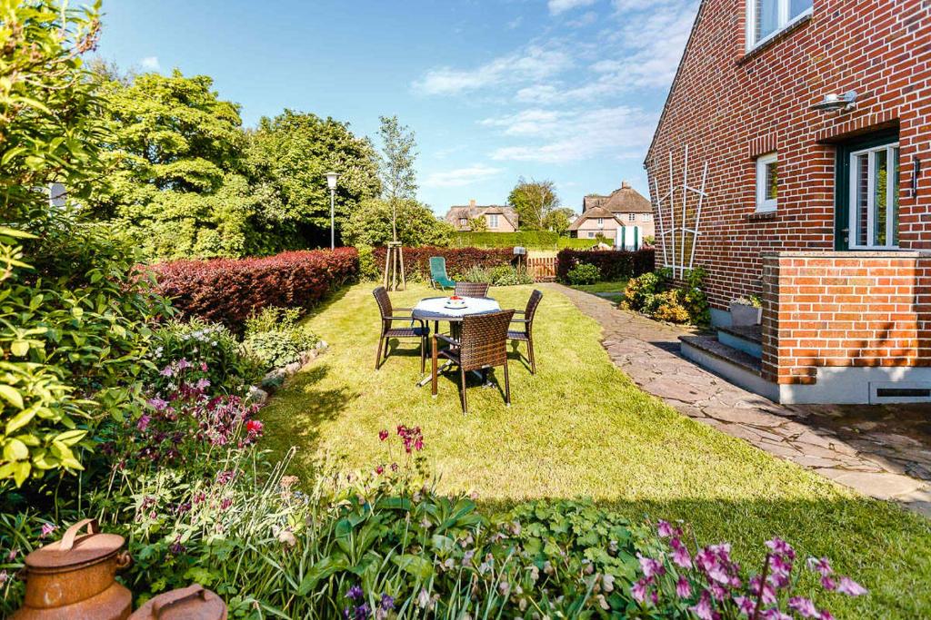 a patio with a table and chairs in a garden at Ferienhaus VOGELKIEKER in Midlum