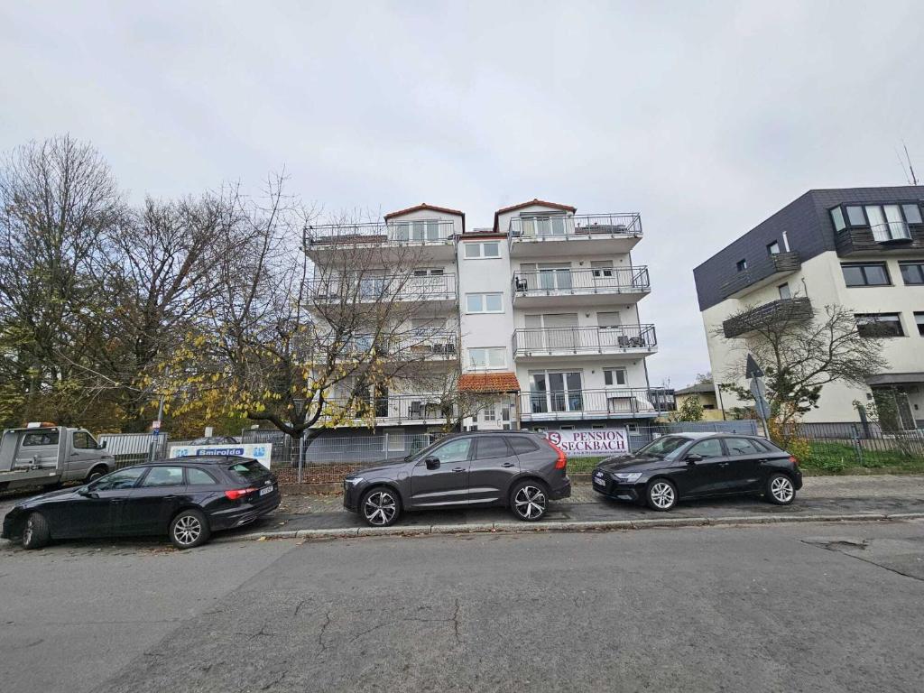 three cars parked in a parking lot in front of a building at Pension Seckbach in Frankfurt/Main