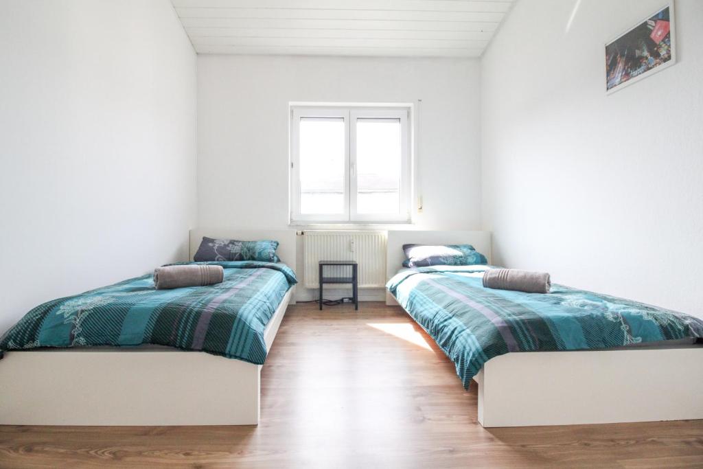 Habitación con 2 camas, paredes blancas y suelo de madera. en nJoy! Sunny & Spacious - Balkon - WLAN - Parkplatz - perfekt für Work & Travel en Göppingen