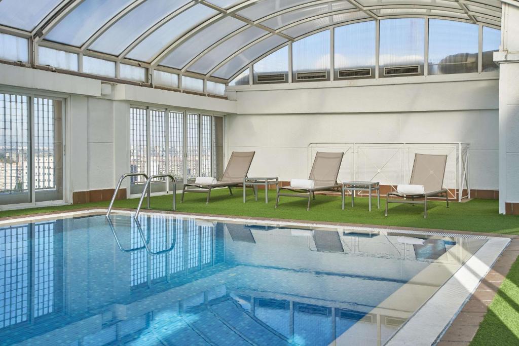 une piscine intérieure avec un plafond en verre dans l'établissement NH Valencia Center, à Valence