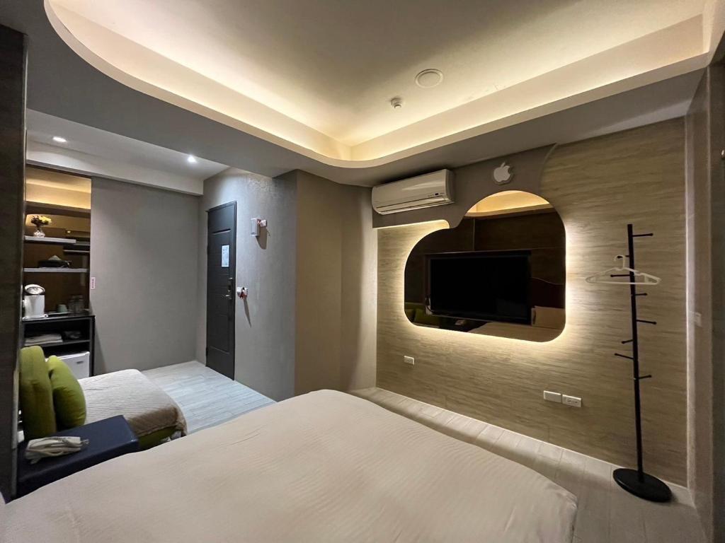 - une chambre avec un lit et une télévision murale dans l'établissement Now and Then Hot Spring Inn, à Jiaoxi