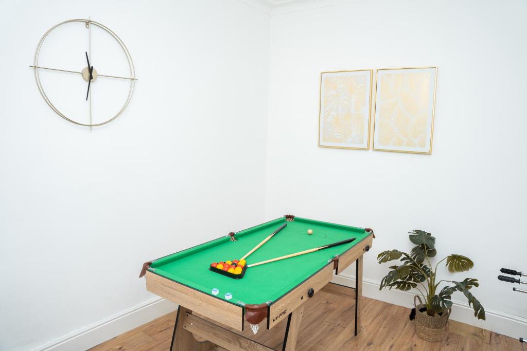 a pool table in a room with a clock at Large Ideal Accommodation for Groups & Contractors in Horsforth