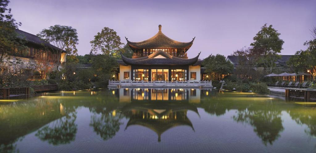 ein chinesisches Gebäude mit einem Teich davor in der Unterkunft Four Seasons Hotel Hangzhou at West Lake in Hangzhou