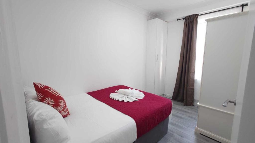 ein Schlafzimmer mit einem weißen Bett mit einer roten Decke in der Unterkunft Eurostar City Apartments in London