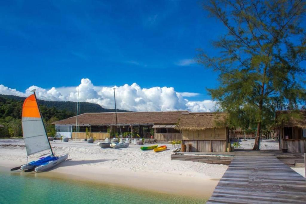 ein Segelboot auf einem Strand neben einem Gebäude in der Unterkunft Sok San Beach Resort in Koh Rong
