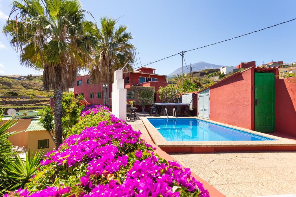 a villa with a swimming pool and purple flowers at Finca la Gaviota - Terazza-Jacuzzi con vistas al teide in Icod de los Vinos