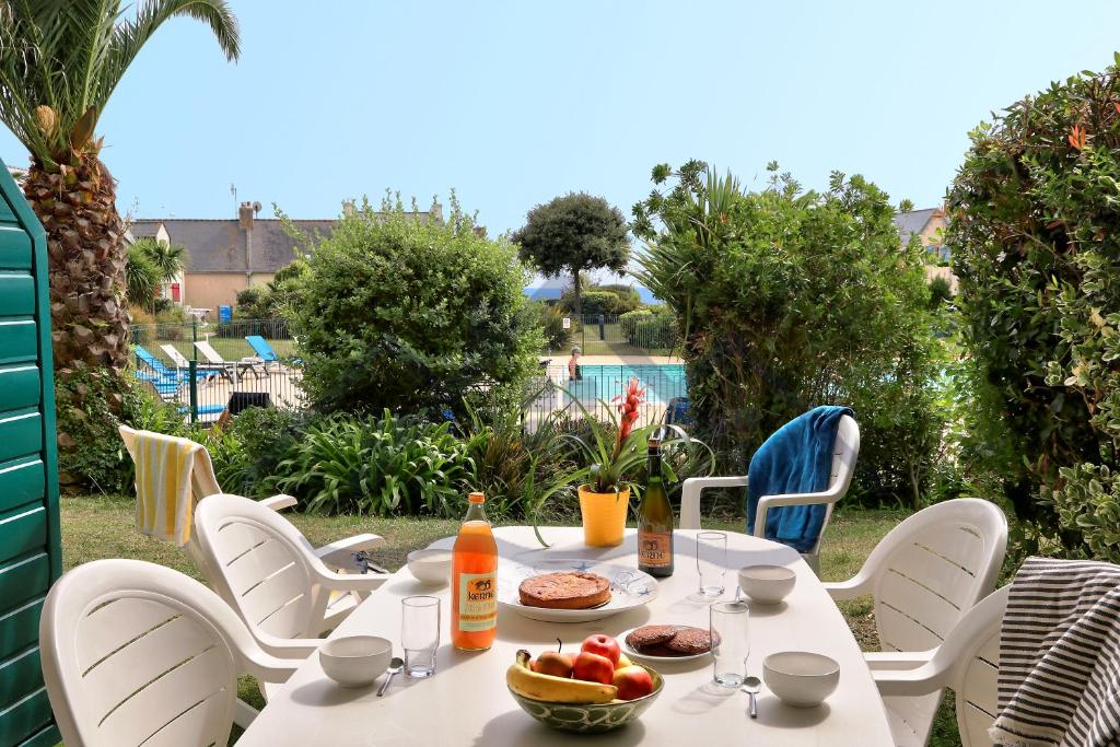 stół z jedzeniem i napojami na patio w obiekcie LocaLise - A06 - Entièrement de plain-pied avec petite vue mer - Donnant sur la piscine et le jardin - wifi inclus - draps inclus - w mieście Guilvinec