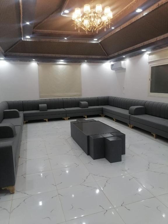 a waiting room with black couches and a chandelier at استراحه لوسيل in Khamis Mushayt