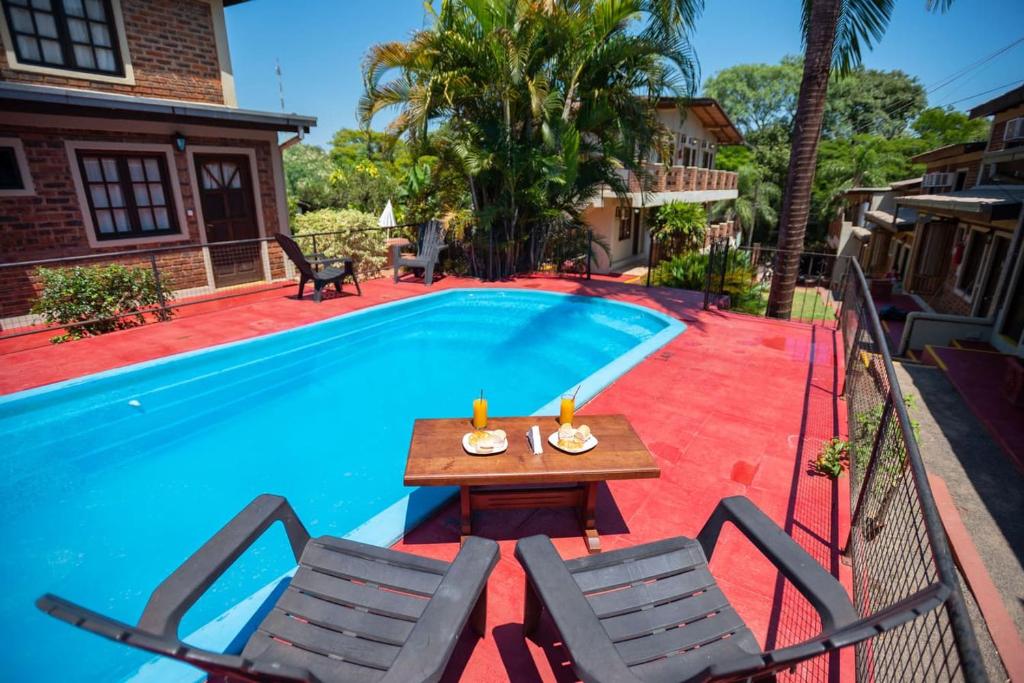 uma mesa e cadeiras ao lado de uma piscina em LOS HELECHOS II em Puerto Iguazú
