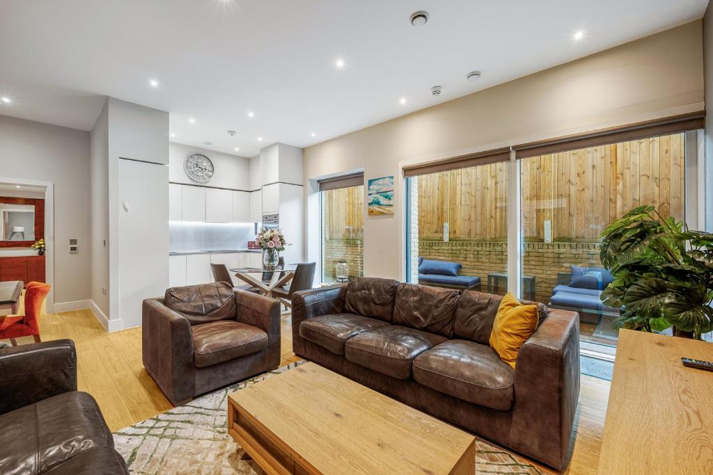 a living room with a leather couch and chairs at Large Modern One Bedroom Apartment (nearly 800 ft) in London