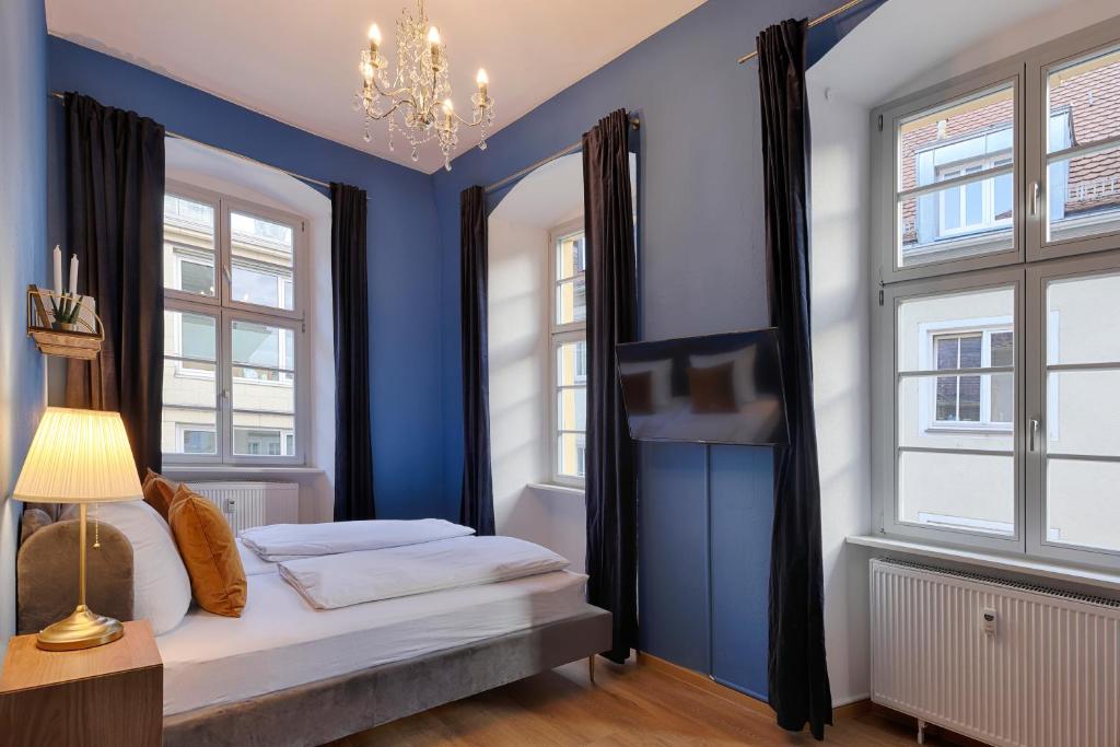 1 dormitorio con paredes azules y 1 cama con lámpara de araña en Balthasar Neumann Apartment - by homekeepers, en Würzburg