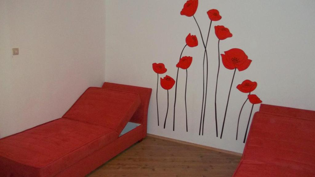 ein Zimmer mit einer roten Couch und roten Blumen an der Wand in der Unterkunft VisegradApartment in Budapest