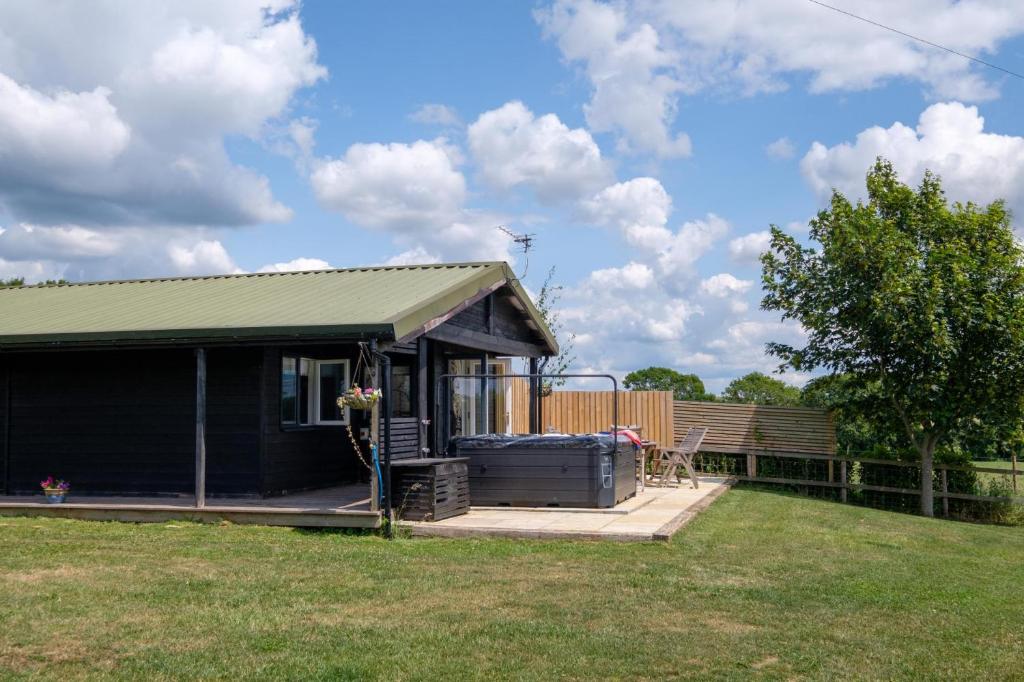 a small black house with a porch in a yard at Ash Lodge - Exclusive Lodge with Hot Tub and stunning views in Bradpole