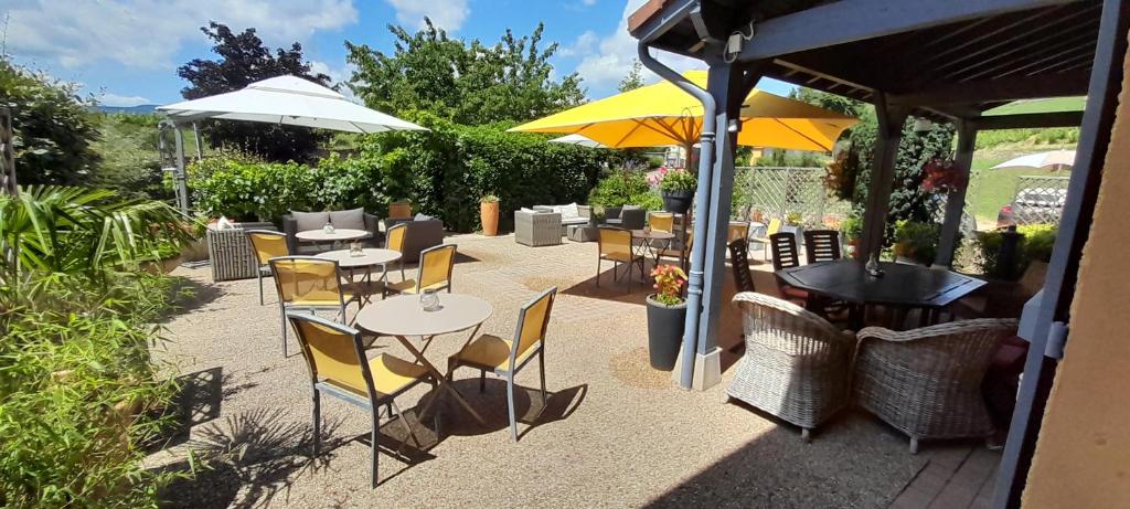 eine Terrasse mit Tischen, Stühlen und Sonnenschirmen in der Unterkunft Hôtel des Vignes in Juliénas