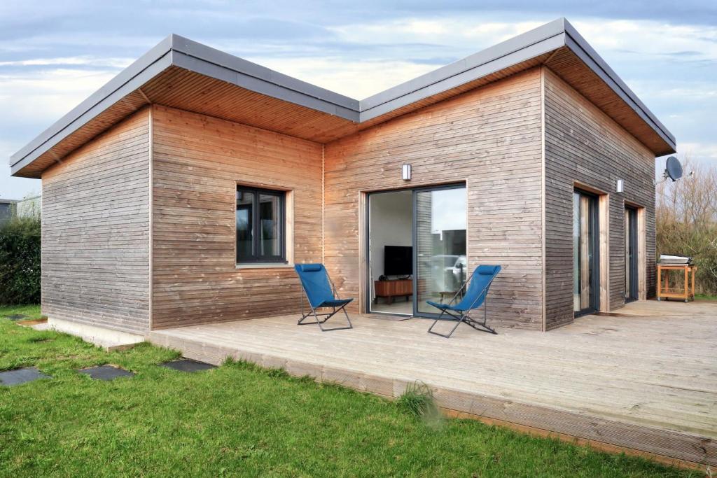 une maison avec deux chaises bleues sur une terrasse dans l'établissement Chez Marie et Philippe - 1km de la plage, à Les Moitiers-dʼAllonne