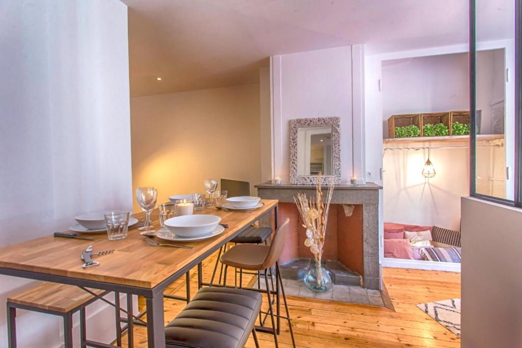 une salle à manger avec une table, des chaises et une cheminée dans l'établissement Le rendezvous des grenoblois, à Grenoble