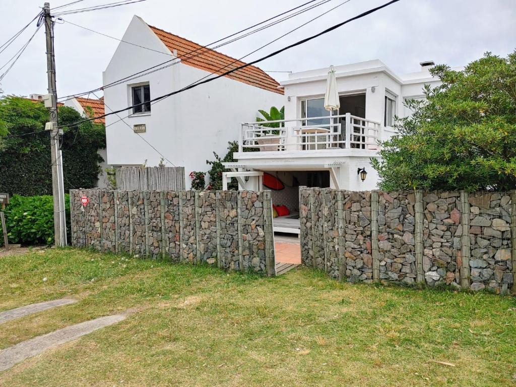 uma casa branca com uma cerca de pedra à frente. em Nirvana em Punta del Este