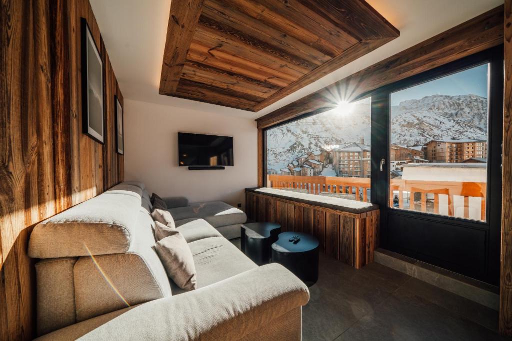 een woonkamer met een bank en een groot raam bij Appartement Pixel by ExplorHome in Tignes