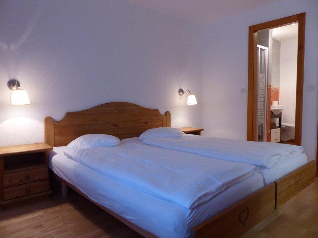 a bed in a bedroom with two lamps and a mirror at Appartement de 3 pièces au Residence Panorama in Villars-sur-Ollon
