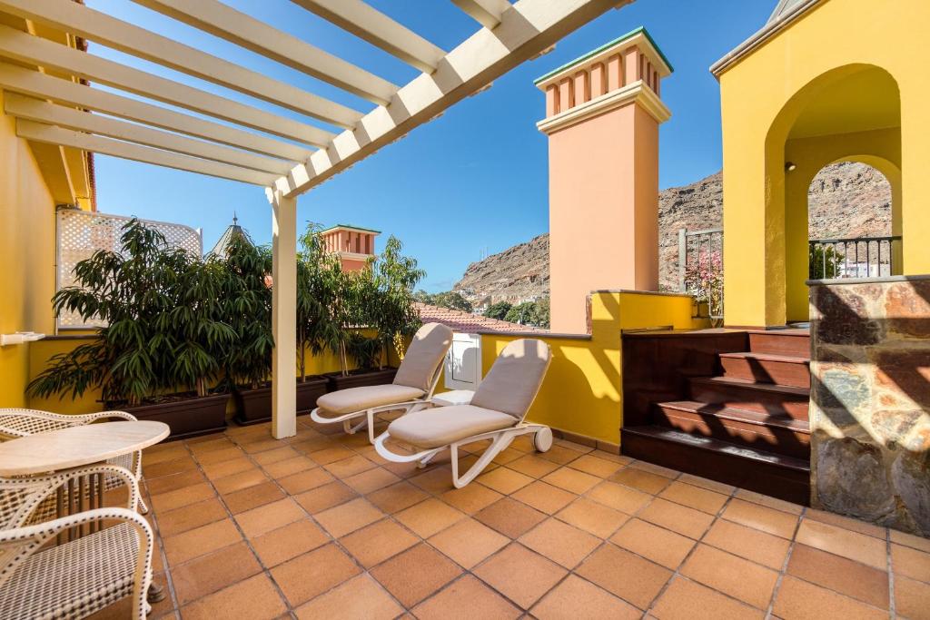 a patio with two chairs and a fireplace at Hotel Cordial Mogán Playa in Puerto de Mogán