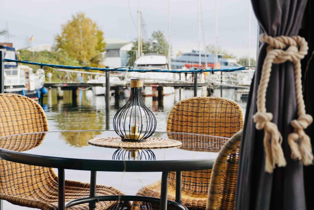 uma mesa de vidro com cadeiras e um vaso sobre ela em Hausboot AHOY Masal em Lübeck