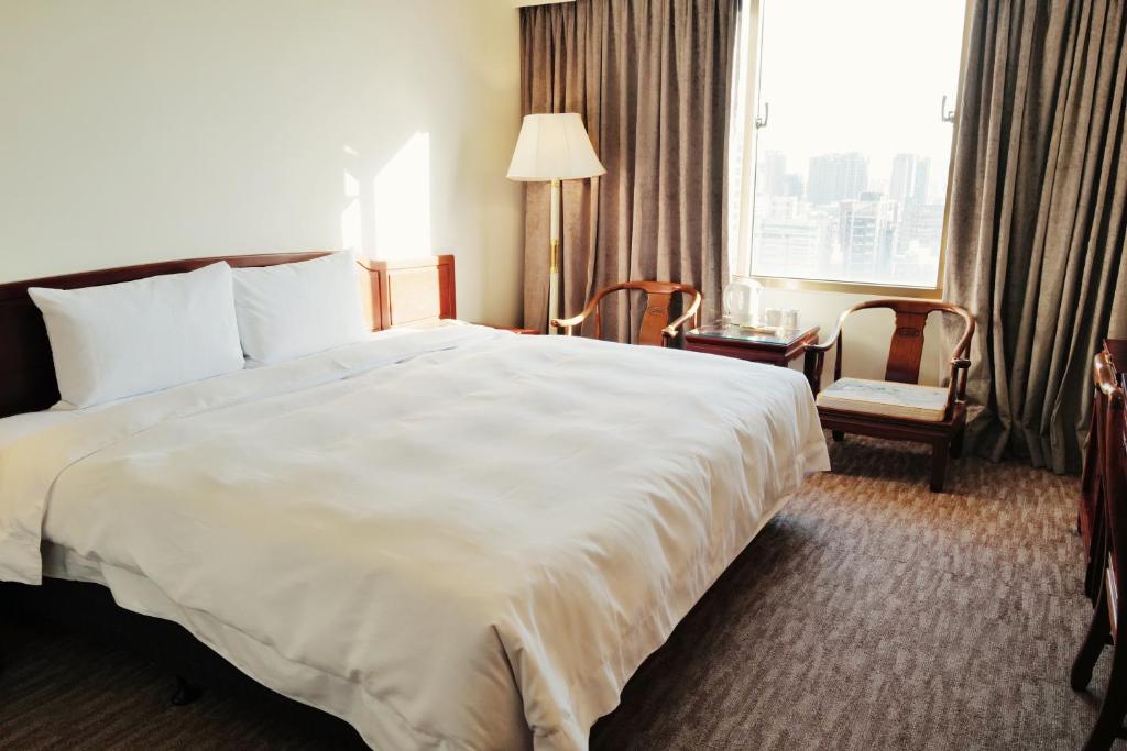 una habitación de hotel con una gran cama blanca y una ventana en T Hotel, en Taichung