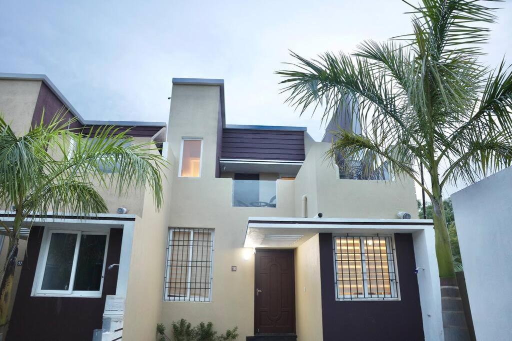 a white house with palm trees in front of it at 2bhk leisurehouse near Auroville in Marakkānam