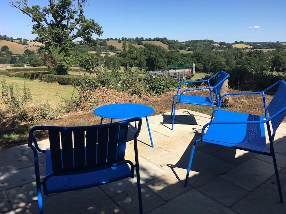 - deux chaises bleues et une table sur une terrasse dans l'établissement Beautiful home with stunning lake and valley views, à East Harptree