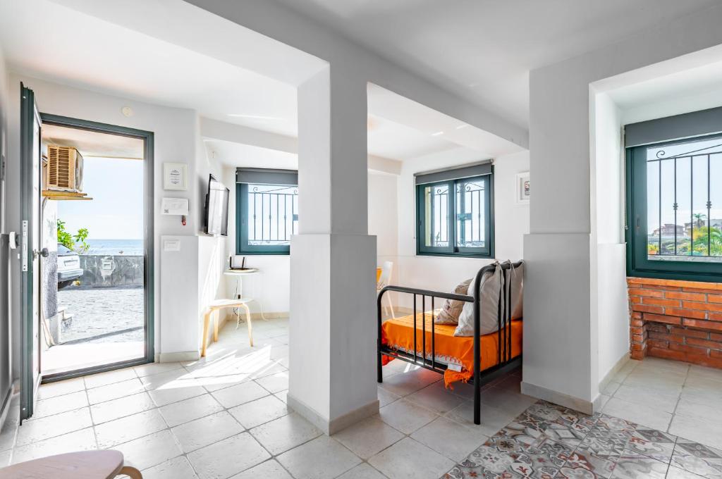 een slaapkamer met een bed in een kamer met ramen bij Seafront Apt with View in Aci Castello in Aci Castello