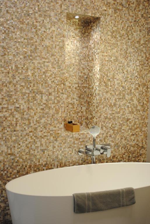 a bath tub in a bathroom with a tile wall at Les Suites Massena in Nice