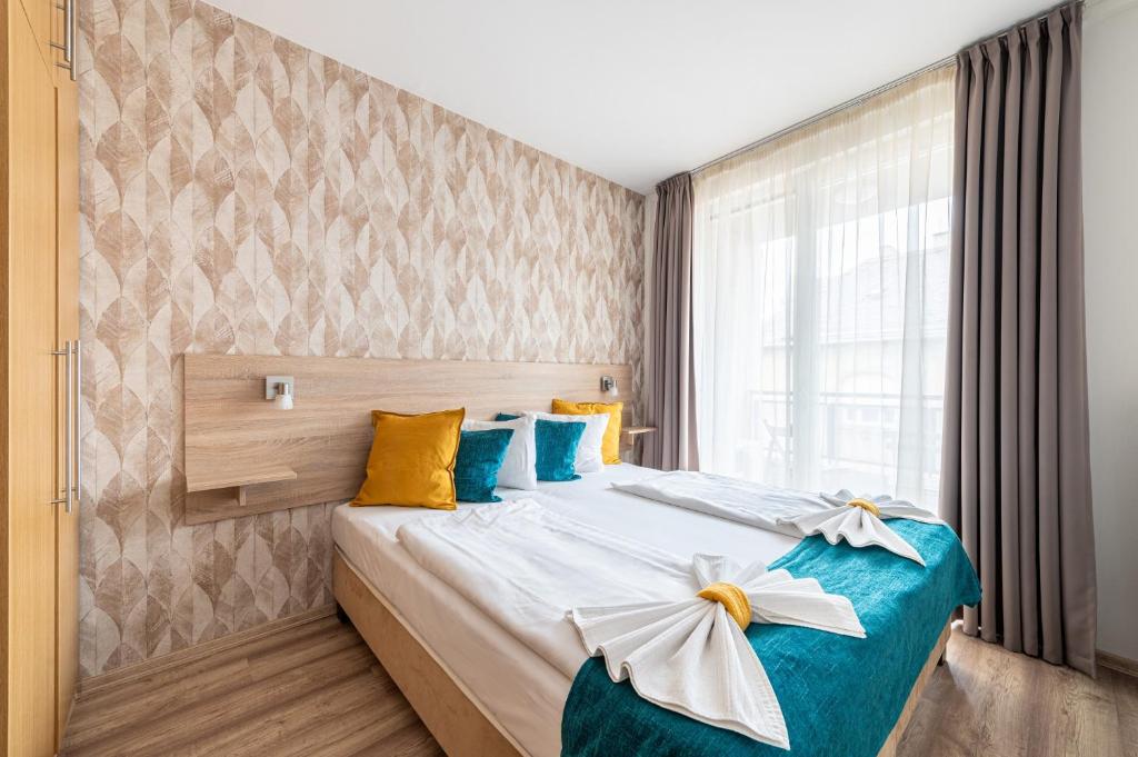 a bedroom with a bed with blue and yellow pillows at Nova Apartments in Budapest