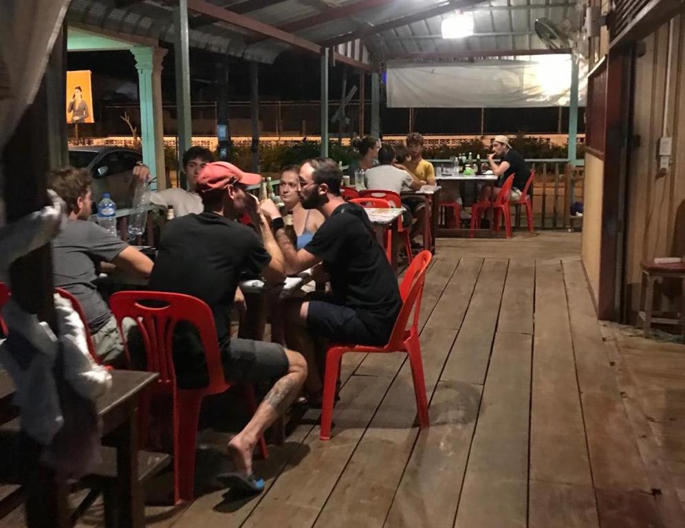 een groep mannen aan een tafel in een restaurant bij Somewhere over the river in Ban Houayxay
