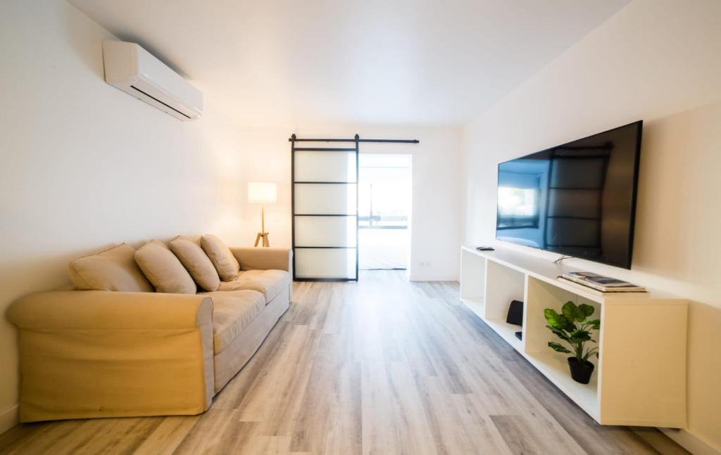 een woonkamer met een bank en een flatscreen-tv bij Apartamento Guia Atrium Cascais in Cascais