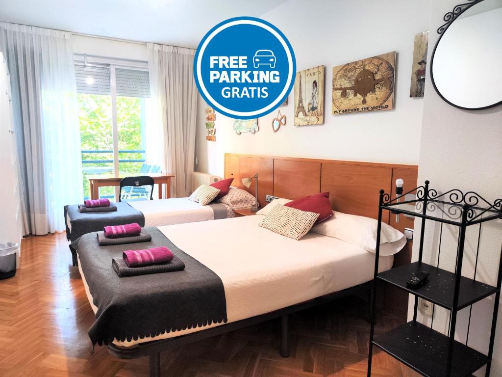 a bedroom with two beds and a sign that says free parking crafts at Mirasierra Suites Pamplona in Pamplona