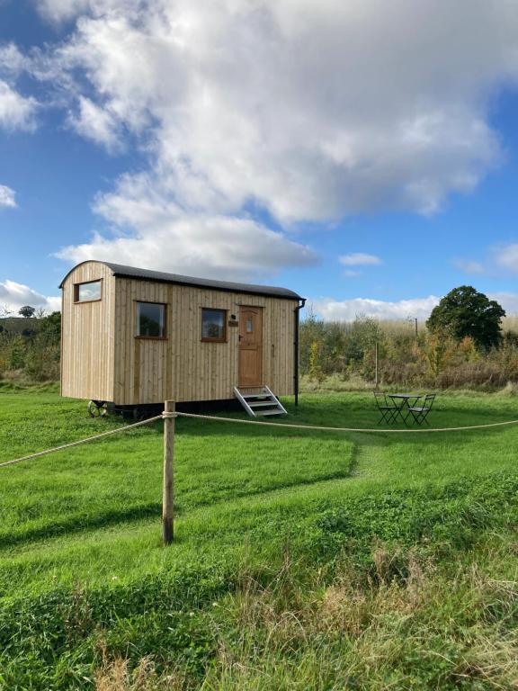 a tiny house in a field with a sign at Shepherd's Huts in Barley Meadow at Spring Hill Farm in Oxford