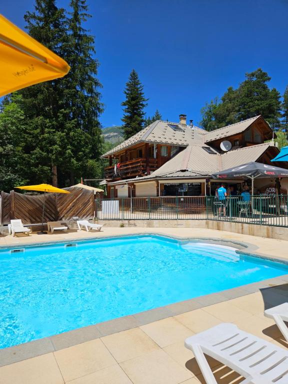 une piscine avec des chaises et une maison dans l'établissement Mobil Home XXL 4 chambres - Camping Les Relarguiers, à Beauvezer