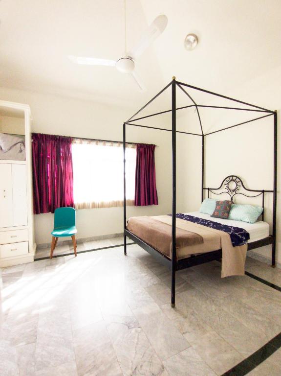 - une chambre avec un lit à baldaquin et une chaise bleue dans l'établissement Casa Tzunun Airport Junior Suite, à Cancún