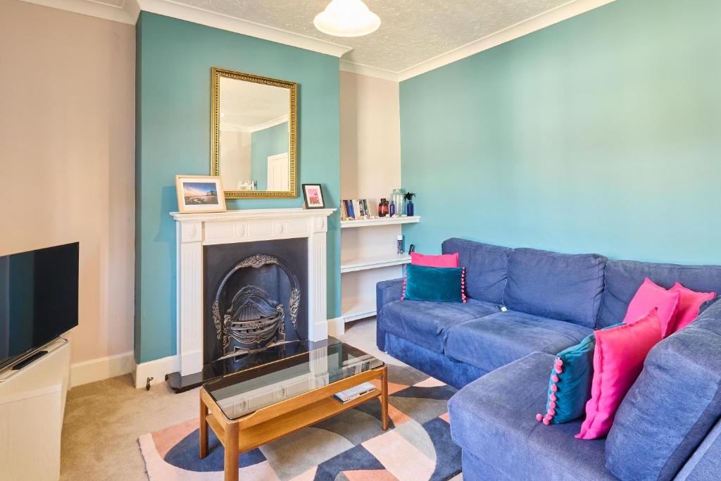 a living room with a blue couch and a fireplace at Host & Stay - Westbrook Road in Margate