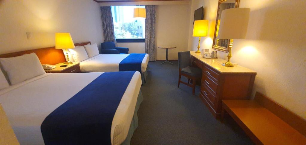 A traditional two-bed room with a dresser desk and a window at the far end.