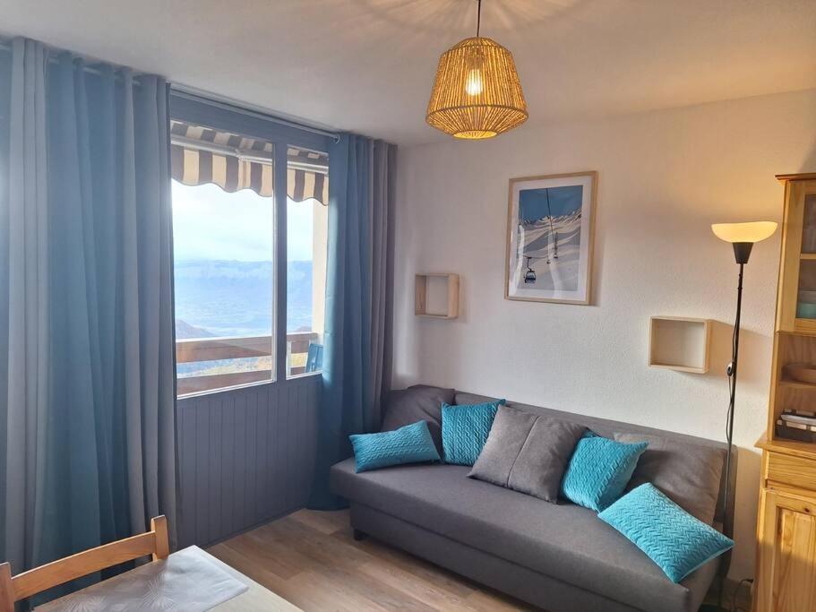 a living room with a couch and a window at Studio rénové - Pied des pistes - Prapoutel - Les 7 laux in Les Adrets