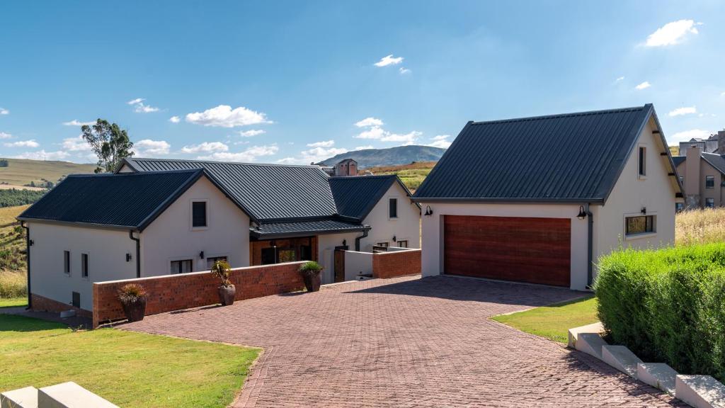 a house with a driveway and a garage at Highland Gate Eagles Breeze in Dullstroom