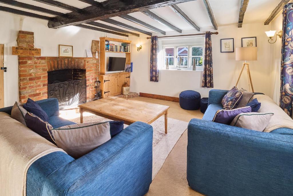 a living room with two blue couches and a fireplace at Host & Stay - Bere Cottage in Canterbury
