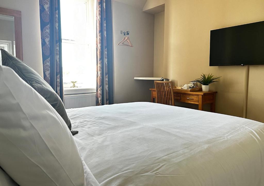 a bedroom with a white bed with a flat screen tv at Station Lounge & Rooms in Clitheroe