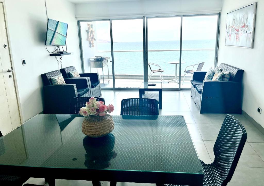 una sala de estar con mesa y sillas y el océano en 501 Velas Primera Fila Vista Bahía Paracas 110 Metros - 501 T1, en Paracas
