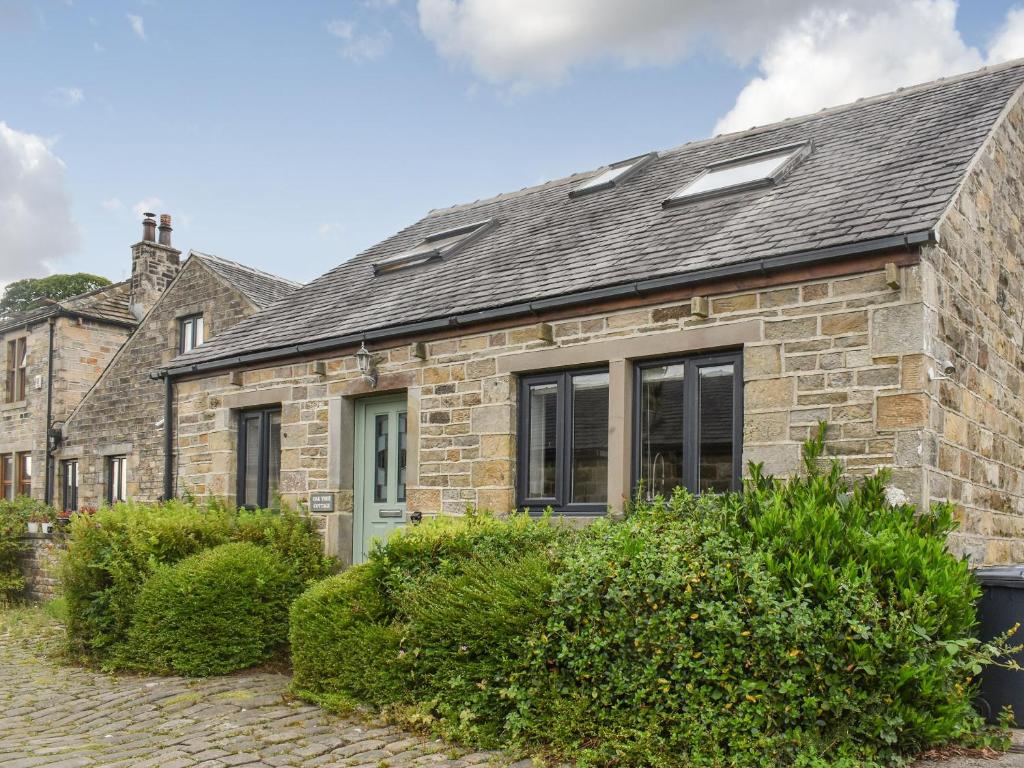 ein Steinhaus mit grauem Dach in der Unterkunft Oak Tree Cottage in Brierfield