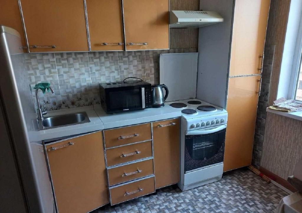 a small kitchen with a stove and a microwave at Apartment near the airport - Квартира около аэропорта in Dushanbe